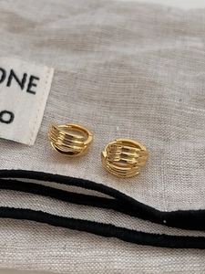 Détail macro de boucles d'oreilles dorées géométriques sur un tissu texturé neutre