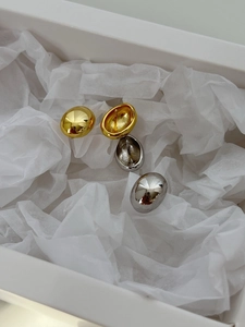 Macro detail of gold and silver S925 sterling silver bean stud earrings with polished finish