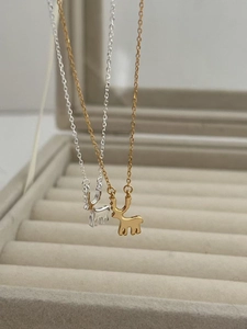 Détail des colliers pendentifs cerf en argent et or sur un coffret de rangement bijoux