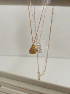 Dettaglio dei ciondoli a sacchetto portafortuna in oro e argento con incisione Fu