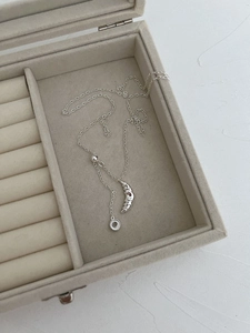 Macro shot of silver croissant pendant necklace with textured spiral in jewelry box
