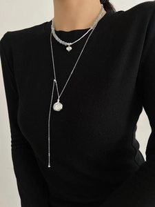 Détail de colliers superposés en argent S925 avec pendentifs en forme de cœur et de disque