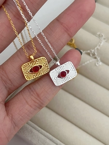 Close-up of gold and silver sunburst necklaces with a red gemstone in a jewelry box