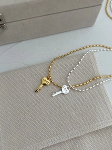 Détail de pendentifs clé cœur en or et argent avec gravure LOVE sur chaînes à billes