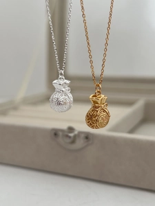 Dettaglio dei ciondoli a sacchetto portafortuna in argento 925 e oro vintage con carattere Fu