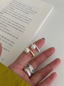 Close-up of S925 sterling silver pearl ring and blue heart pattern ring on hand