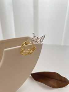 Artistic s925 silver irregular rings in gold and silver finish hanging on a ceramic vase