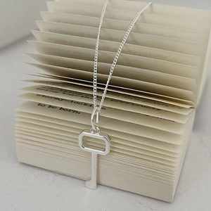 Elegant 925 sterling silver key pendant necklace displayed on artistic book pages