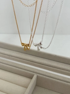 Detailed comparison of gold and silver bow necklaces on soft velvet jewelry background