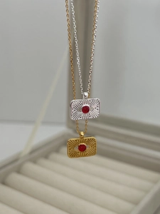 Detail of 925 sterling silver compass pendants with red gemstones in gold and silver