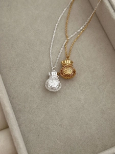 Dettaglio di collane con pendente a sacchetto portafortuna in argento S925 dorato