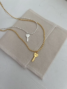 Détail des pendentifs clés en forme de cœur dorés et argentés sur colliers à maillons