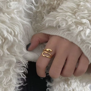 Polished wavy gold open ring for women with minimalist fluid design on a fashion background