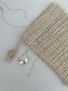 Détail du pendentif bouteille en argent S925 avec texture martelée sur fond blanc épuré