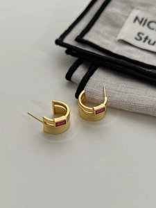 Detail of matte gold C-shaped sterling silver earrings with rectangular pink zircon stones