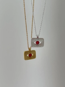 Detail of 925 silver sun compass pendant with red gemstone in gold and silver finish