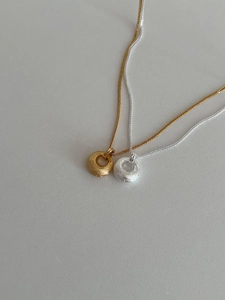 Vue détaillée des pendentifs circulaires mats en or et argent avec de fines chaînes tressées