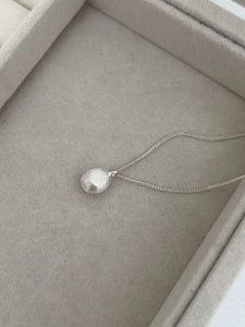 Close-up of S925 sterling silver oval pendant with matte brushed texture on soft velvet