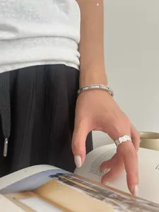 Detail of 925 sterling silver clover bracelet and wave ring on a fashion model
