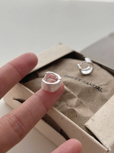 Macro shot of S925 sterling silver earrings with a brushed finish and authenticity mark