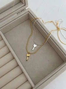 Gros plan de colliers chaîne olive dorée et argentée avec pendentifs clé cœur LOVE
