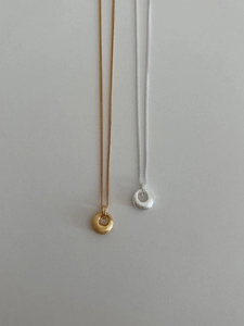 Vue détaillée des colliers avec pendentifs cercles géométriques brossés en argent et or