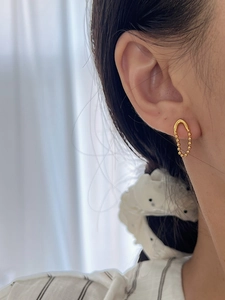 Gros plan de boucles d'oreilles dorées en chaîne en V avec perles sur un mannequin