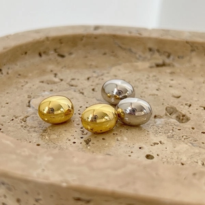 Minimalist oval metallic stud earrings in polished gold and silver finishes on stone