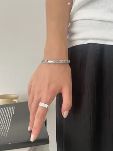 Detailed view of silver cuff bracelet with clover charms and geometric stripe ring