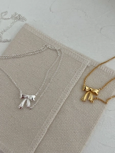 Detailed view of silver and gold ribbon bow pendants with realistic textured folds