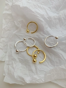 Close-up of minimalist gold and silver 925 sterling silver bead rings on white paper
