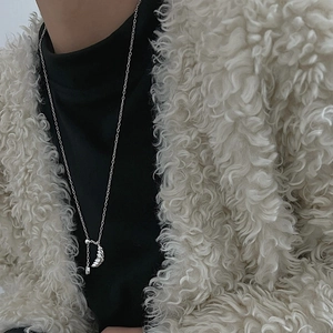 Silver croissant pendant necklace on model wearing a white faux fur coat for women