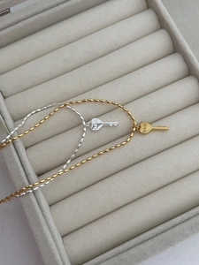 Détail de colliers clés en cœur argent et or sur un présentoir en velours gris