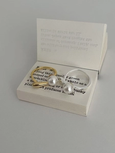 Detail of two S925 sterling silver pearl rings in gold and silver on a vintage book prop