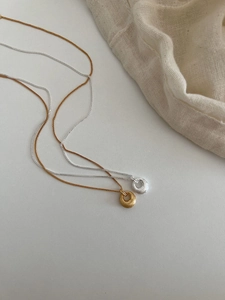 Détail de pendentifs cercles en métal brossé minimalistes en finitions or et argent