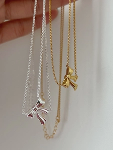 Detail of silver and gold ribbon bow pendants showing delicate metallic textures