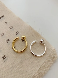 Detailed view of 925 silver and gold bead open rings on a vintage fabric background