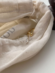 Macro shot of 925 sterling silver asymmetric gourd rings on a beige linen fabric bag