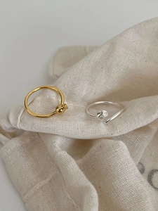 Close-up of gold and silver minimalist twist rings on a textured cotton drawstring pouch