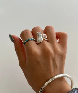 Detailed close-up of 925 sterling silver cat ring and blue beaded ring on a hand