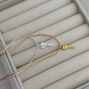 Colliers en or et argent avec pendentif clé gravé LOVE sur support en velours