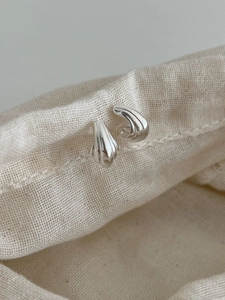 Vue détaillée de boucles d'oreilles en argent S925 avec texture ondulée sur tissu en lin