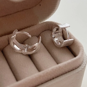 Minimalist polished silver huggie hoop earrings displayed in a brown velvet jewelry box