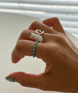 Detailed close-up of a silver cat-shaped ring with beaded turquoise and silver band