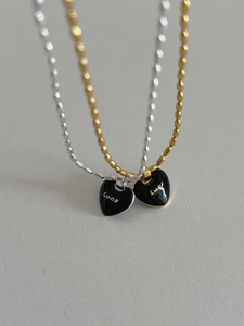 Detail view of gold and silver beaded necklaces with black enamel luck heart pendants