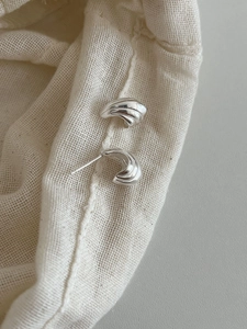Vue détaillée des boucles d'oreilles en argent S925 avec texture ondulée en forme de C