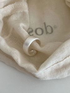 Detailed view of matte brushed S925 sterling silver open ring on a beige linen pouch