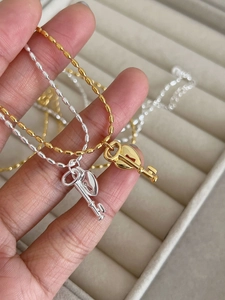 Detail of gold and silver heart-shaped key pendants on beaded chains against a velvet background