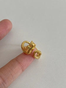 Detail of a gold cat-shaped open ring on finger showing 3D feline curves and texture