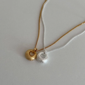 Colliers avec pendentif anneau brossé en or et argent sur fond à texture délicate